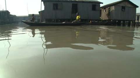 Jib shot. Canoes drift as camera lifts to reveal Makoko waterways Stock Footage 38480466
