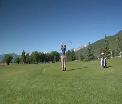 Jib shot of man teeing off on golf course with snowy mountains indistance Stock Footage 21657583