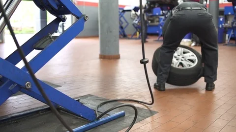 Jib shot of a mechanic putting back a car wheel Stock-Footage 76538461