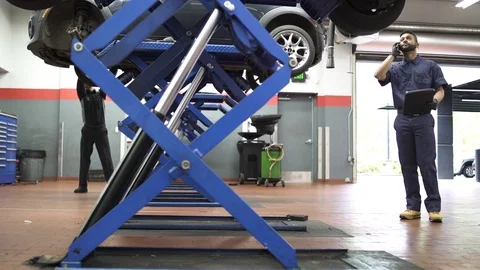 Jib shot of a mechanic talking on cell phone 動画素材 76233007