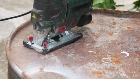 Jigsaw power tool cutting a rusty metal barrel Video stock 335546397