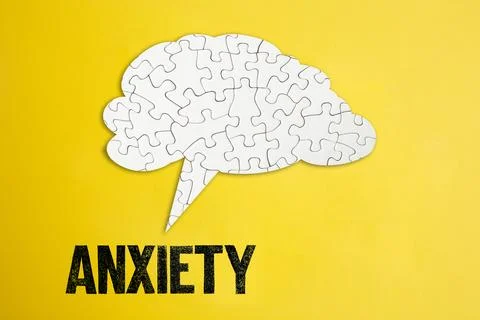 Jigsaw puzzle brain shape speech bubble on yellow cardboard background with.. Stock Photos