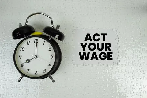 Jigsaw puzzle with a missing piece with "Act Your Wage" and alarm clock on .. Stock Photos