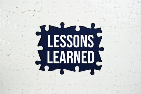 Jigsaw puzzle with a missing piece with "Lessons Learned" on blue background Stock Photos