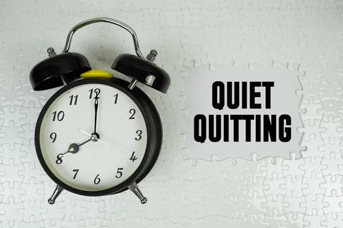 Jigsaw puzzle with a missing piece with "Quiet Quitting" and alarm clock on.. Stock Photos