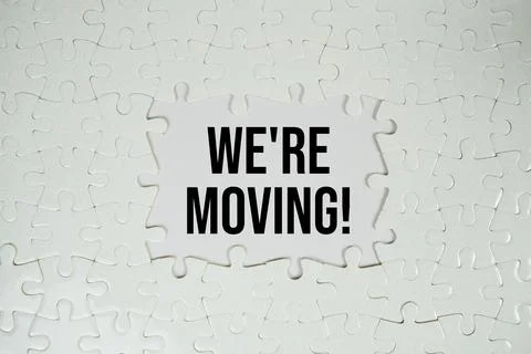Jigsaw puzzle with a missing piece with "We're Moving!" on white background Stock Photos