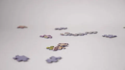 Jigsaw puzzle pieces fall in slow motion onto a white background Stock Footage 170687727