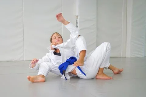 Jiu jitsu student maintaining a collar choke as her partner turns Stock-Fotos