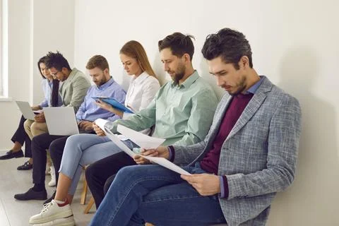 Job applicants sitting in queue waiting for job interview in office Stock Photos