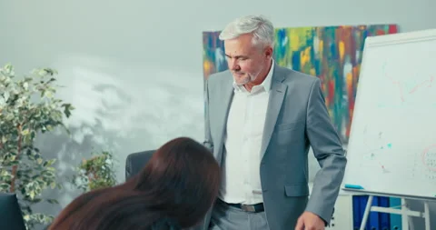 Job interview, elderly boss with gray hair shakes hands with young woman in 库存影片 164894243