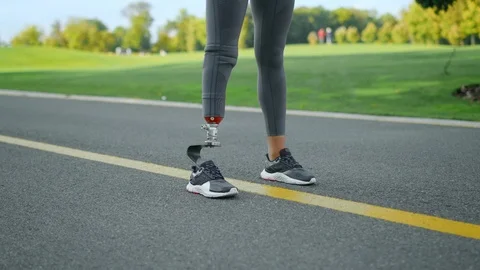 Jogger with artificial limb standing in park. Woman at start position on road Stock Footage 125513120