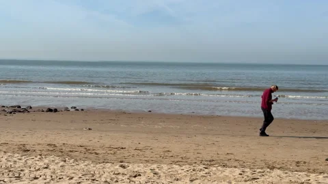 Jogger on beach walks across frame at Formby Sefton Merseyside UK c.. Video stock 331347472