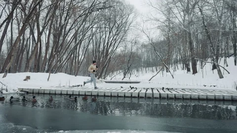 Jogger crossing bridge over river in winter park Stock Footage 147941554