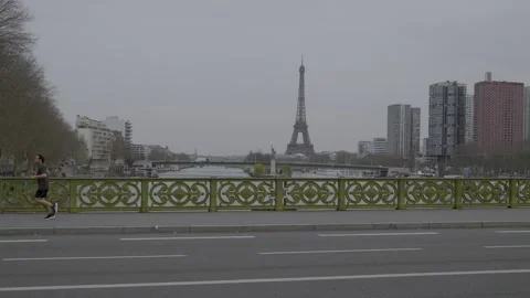 Jogger crossing bridge in Paris with Eiffel Tower in background on an overcast Stock Footage 306645204