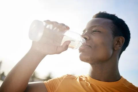 A jogger drinking a bottle of water in the sunlight. An active, healthy African Stock Photos