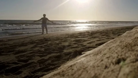 Jogger relaxes on a sand beach at sunset Stock Footage 87560065
