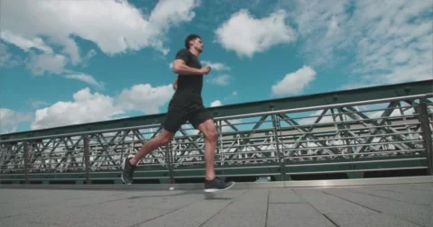 Jogger running over Bridge with moving train in background 스톡 동영상 58861003