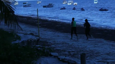 Joggers Run by at Dusk on Beach  (HD) Stock Footage 12604124