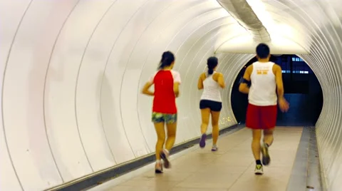 Joggers Running through a Brightly Lit Pedestrian Tunnel 库存影片 57643187