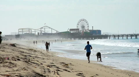 Jogging on Beach with Amusement Park in Background Stock Footage 44346848