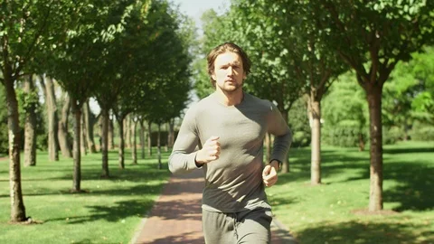 Jogging guy resting after jogging in the park on a background of trees. Video stock 115407939