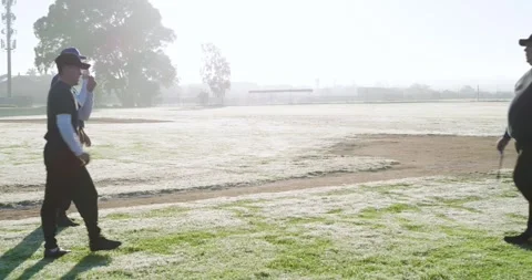 Jogging male players before practice on baseball infield to coach holding Stock Footage 342715947
