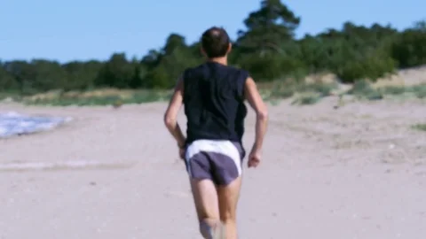 Jogging man on beautiful summer beach is moving away from the camera Stock Footage 82412039