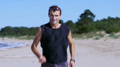 Jogging man on beautiful summer beach is approaching to the camera 库存影片 82412079