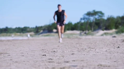 Jogging man on beautiful summer beach is moving straight to the camera Stock Footage 82412510