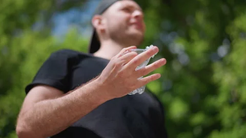 Jogging Man Rests With Water, Man In Summer Park Stops To Drink Water After Stock Footage 324754639