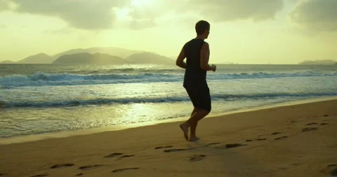 Jogging on the sand on the beach at sunset against the backdrop of the beautiful Stock Footage 146876000