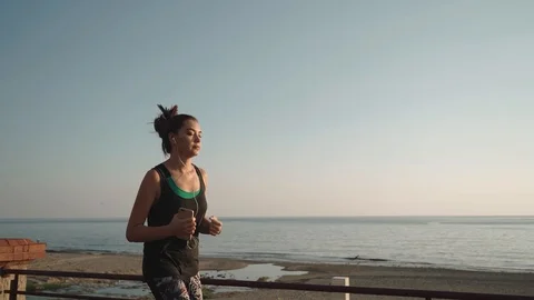 Jogging at sunset on the waterfront. The girl running the seashore. Stock Footage 125365053