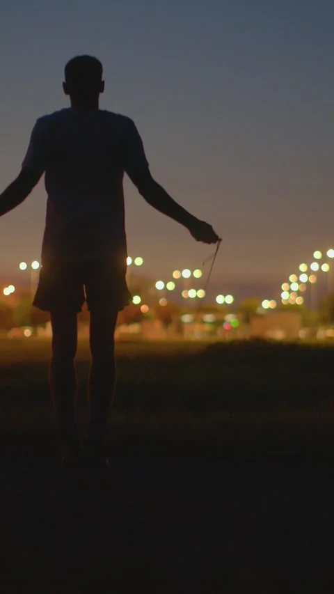 Jogging under citylights, Runner monitors progress during workout Stock Footage 324591890