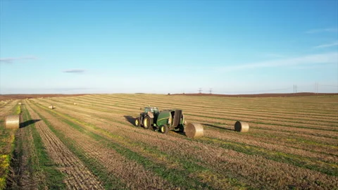 John Deere Tractor with round baler making Hay Bales in an agricultural field Stock Footage 252769099