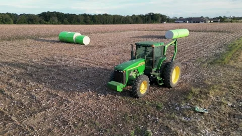 John Deere tractor transporting round cotton modules in harvested cotton field Stock Footage 331650363
