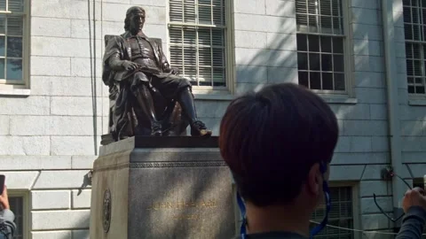 John Harvard's statue surrounded by many visitors and tourists Stock Footage 305432817