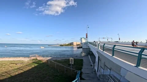 Johns Pass draw bridge man on bike passes boats in ocean Stock Footage 250051135