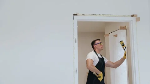 Joiner assembling a doorpost or jamb between two rooms in new apartment Stock Footage 132692930