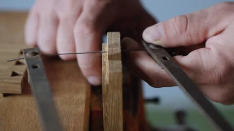 A joiner cuts out a dovetail joint on an oak plank with a hand jigsaw.handmad Stock Footage 144244574