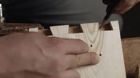 A joiner cuts out a dovetail on a pine board with a chisel. Stock Footage 166340968