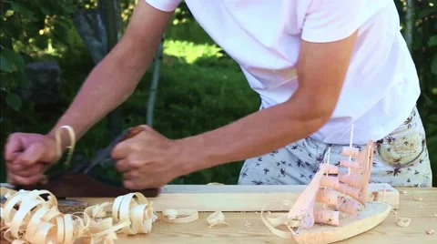 Joiner man works plane with block of wood chips suffer Stock Footage 65431997