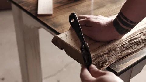 Joiner processes the edges of an oak wood board with spokeshave. carpenter us Stock Footage 166082296