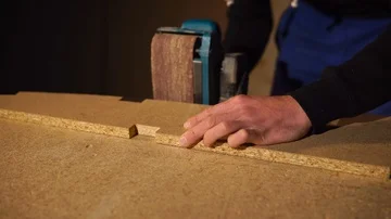 Joiner is processing slices of a timber part of furniture using grinding machine Stock Footage 86034428