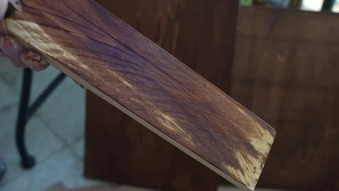 Joiner in transparent gloves covering processed wooden plank with oil-based Stock Footage 208427117