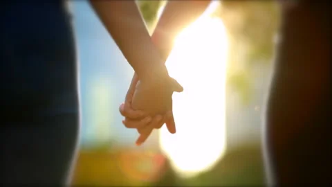 Joining hands together in sunlight flare. Close-up of two people uniting for  Stockbeeldmateriaal 139083408