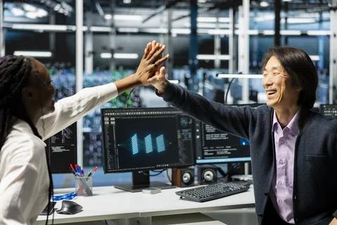 Jolly data center programmers doing high five, happy after finishing AI training Stock Photos