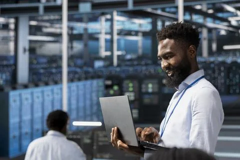 Jolly data center software developer monitoring system performance with laptop Stockfoto's