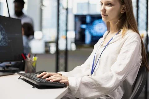 Jolly junior dev in office using AI on computer to streamline app development Stock Photos