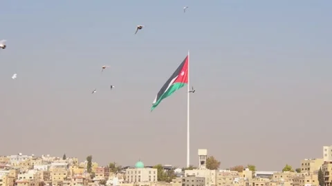 Jordan national flag on giant flagpole above Amman skyline cityscape Middle.. Stockbeeldmateriaal 330259953