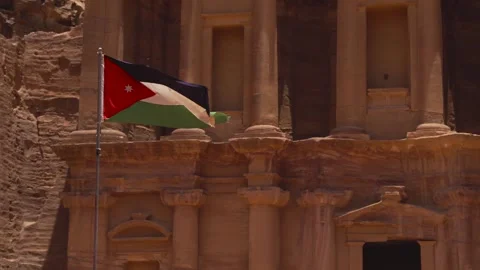 Jordanian flag waving in wind in front of the ancient rock-carved Treasury Stock Footage 309760225